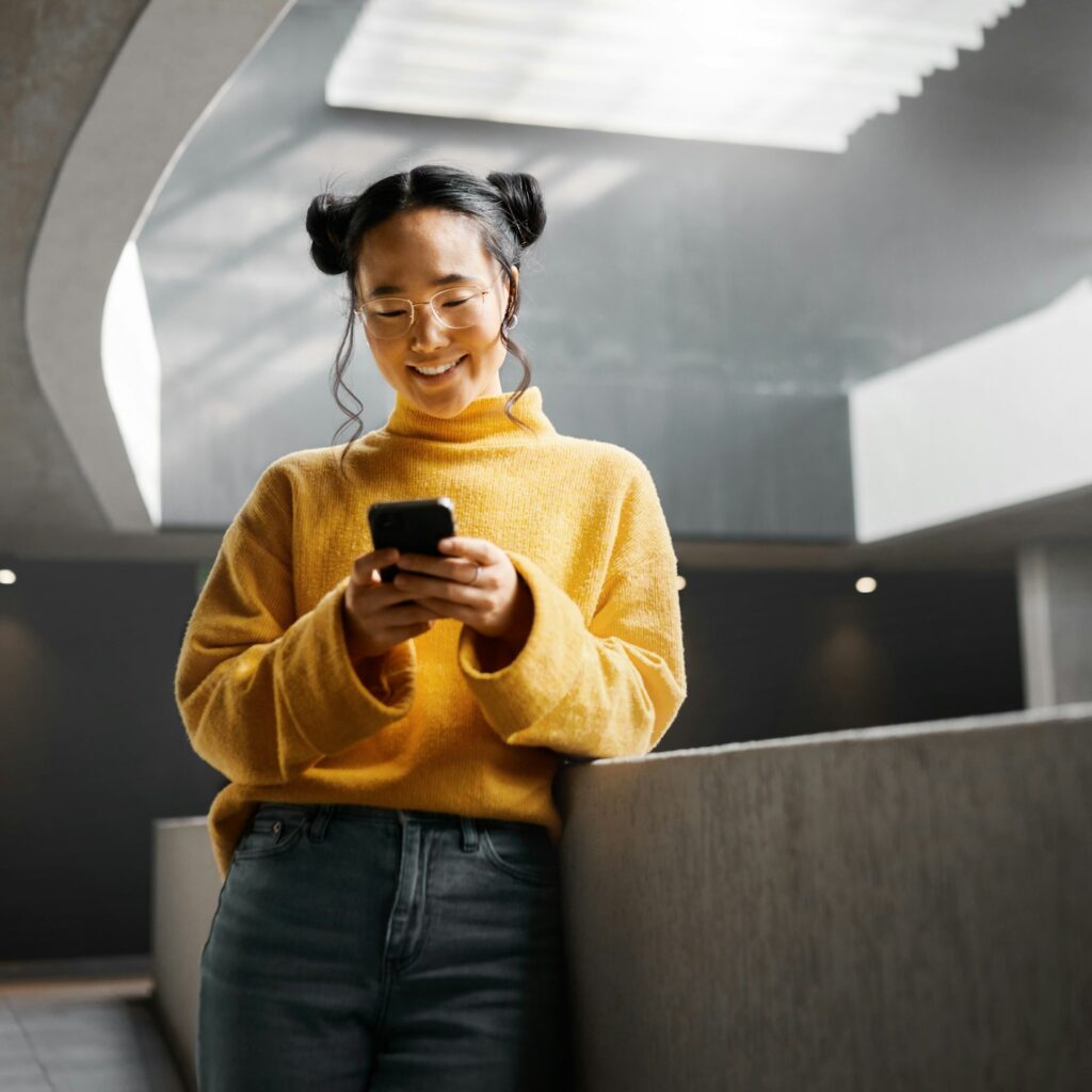 Happy, woman and texting on phone in office building, relax while on internet, search and reading.